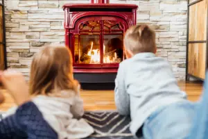 Kids laying in front of a gas stove by Vermont Castings