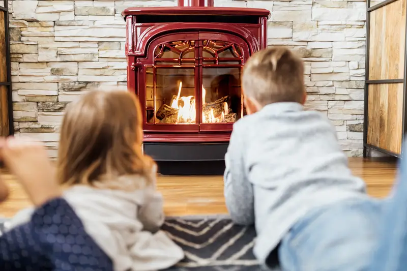 Kids laying in front of a gas stove by Vermont Castings