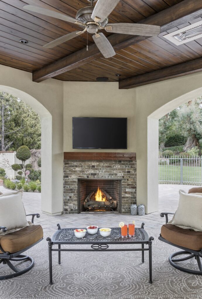 Outdoor room with tv above gas fireplace with relaxing chairs and delicious beverages.