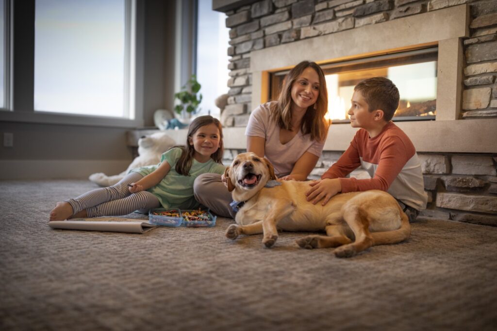Family relaxing together in front of their gas fireplace with their yellow lab dog
