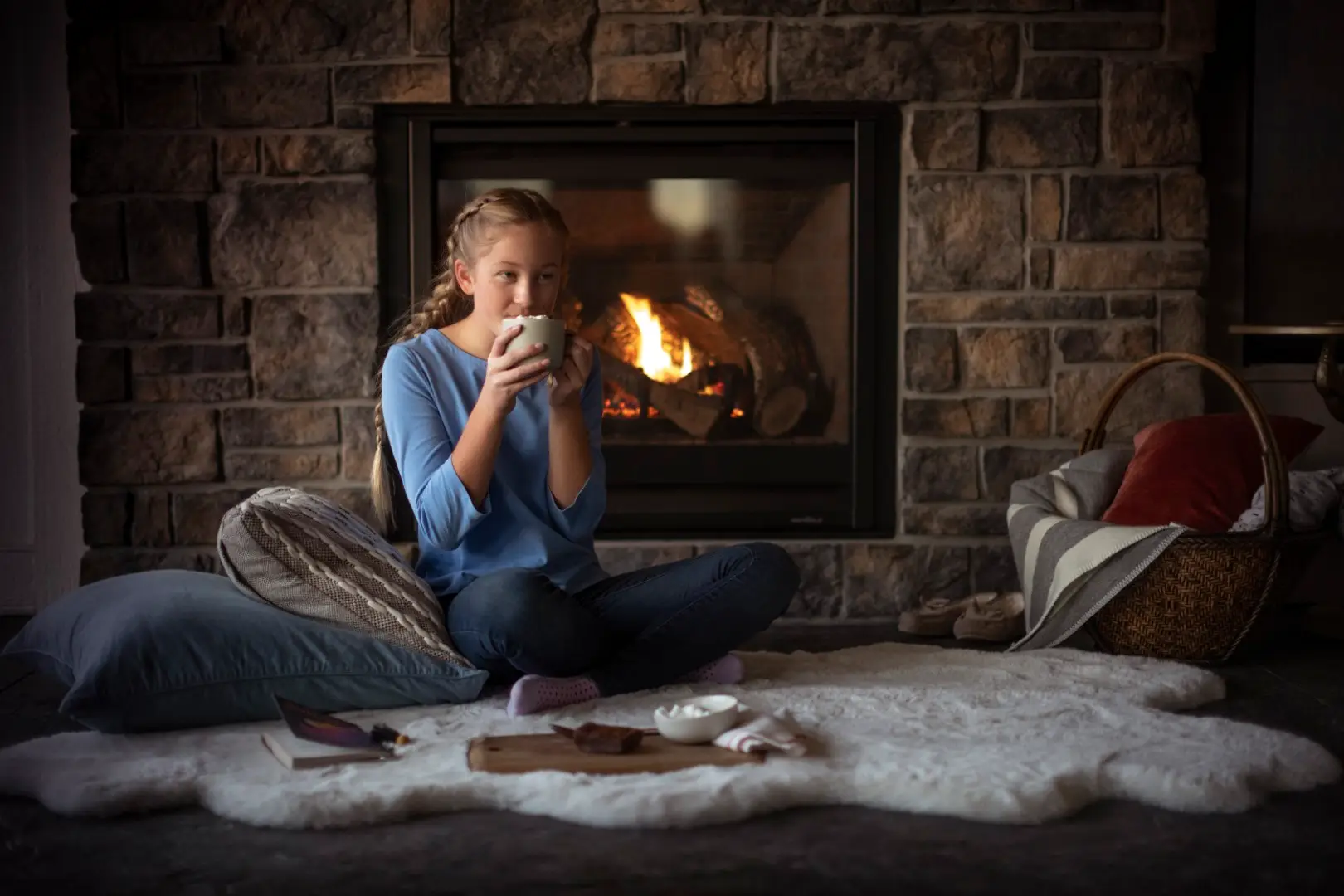 Little girl drinking hot cocoa in front of fireplace