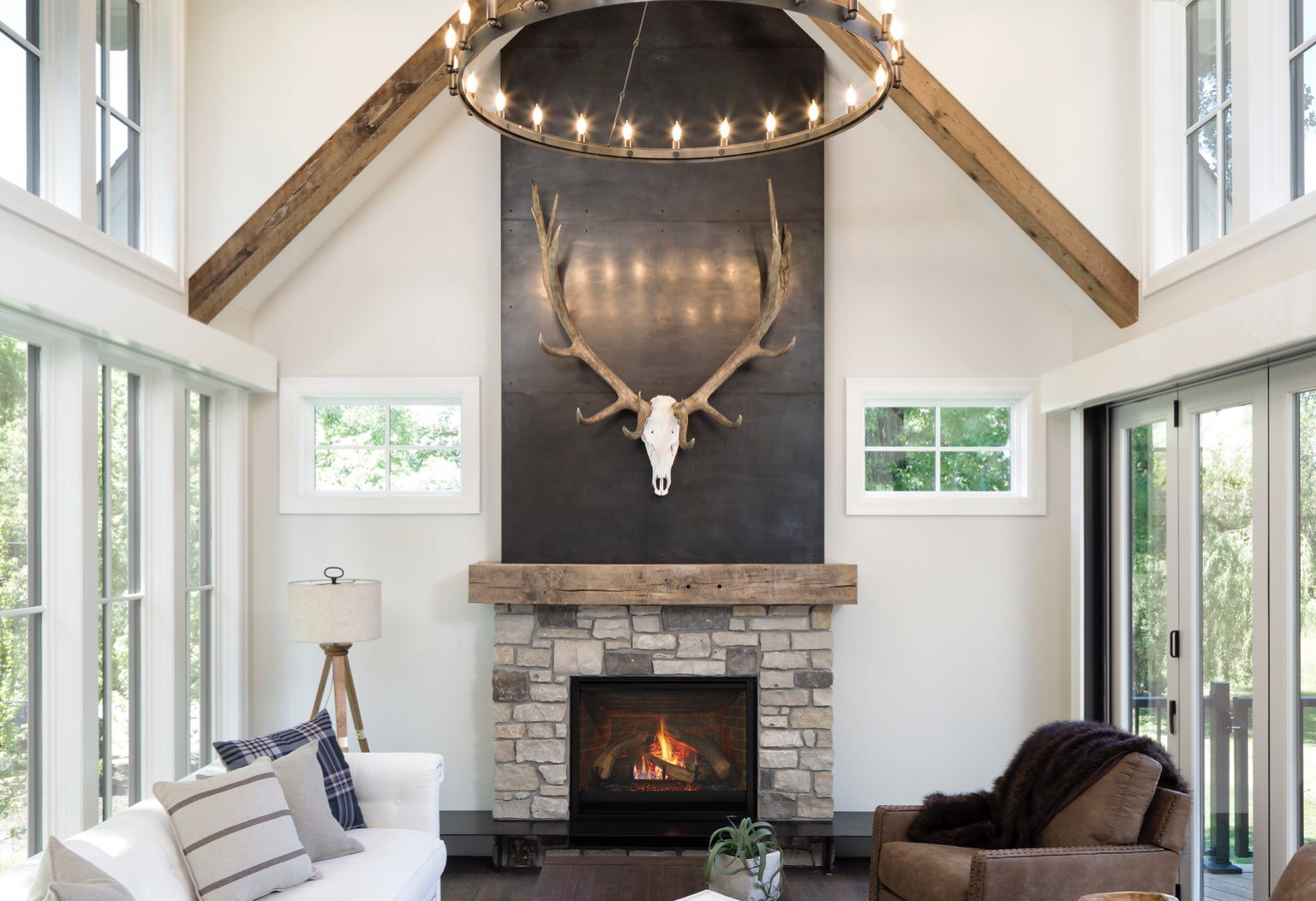 Modern farmhouse great room with classic gas fireplace in two-story hearth wall with windows on each side of the space.