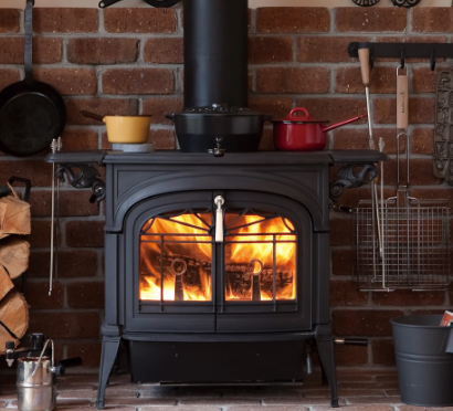 Vermont Castings Encore in Classic Black with a warm wood fire burning.