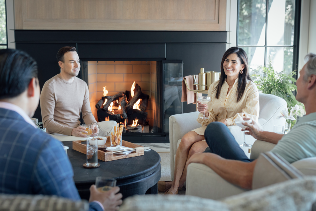 People casual drinking next to open fireplace with gas logs