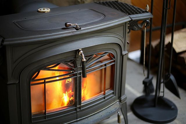 vermont castings epa certified efficient freestanding cast iron black wood stove close up with fire burning and black toolset nearby