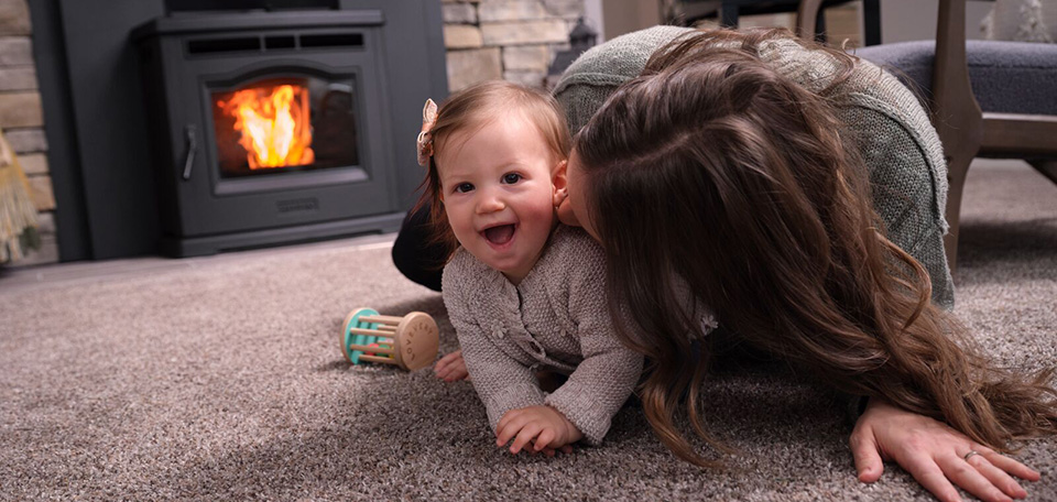 pellet fireplace insert p42 harman with mom and baby laying in front of the fire smiling and having fun